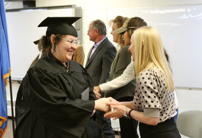 Tina Lugo, left, shakes hands with Kendra Ringstmeyer of the Department of Labor during a graduation ceremony for Department of Corrections precision machining graduates on May 8, 2023 in Pierre. South Dakota Searchlight photo by John Hult