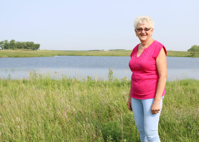 Carolyn Eck stands in front of the land she enrolled in the Conservation Reserve Program in 2019 on her property northwest of Watertown. She currently has 140 acres in the program. South Dakota News Watch photo by Abbey Stegenga