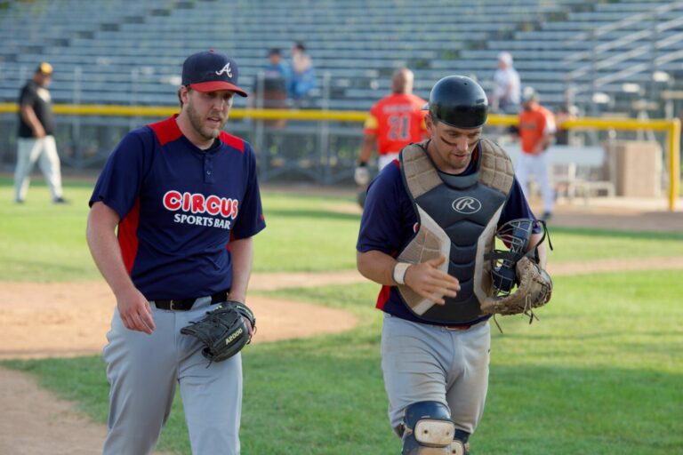 Kelly Coates, right, has a chat with Circus Sports Bar starting pitcher Lucas Heiser after the top of the third inning during a baseball game against Miller on Sunday, July 9 at Fossum Field. Photo by Robb Garofalo