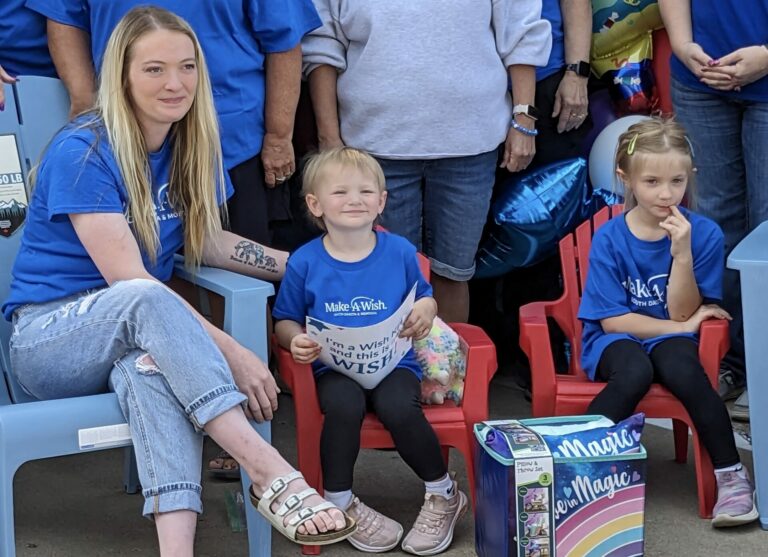 Baelyn Schwab, 3, smiles for photos after being shown her camper from Make-A-Wish South Dakota. At left is her mom, Kelsea, and her sister Kennedy to on the right. Aberdeen Insider photo by Scott Waltman