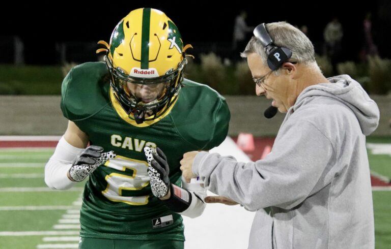 Aberdeen Roncalli head coach Billy Young goes over the play call with Jett Johnson during a game against Webster on Thursday, Oct. 5 at Dacotah Bank Stadium. The Cavaliers open the Class 11B playoffs by traveling to Wagner Thursday night. Aberdeen Insider photo by Robb Garofalo
