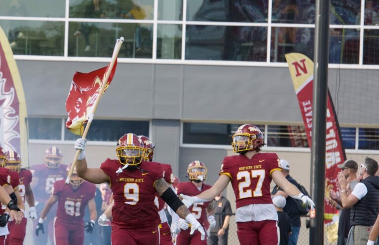 Ian Marshall (center) leads the Northern State Wolves onto the field for their game against Mary Saturday, Sept. 16 at Dacotah Bank Stadium. Aberdeen Insider photo by Robb Garofalo
