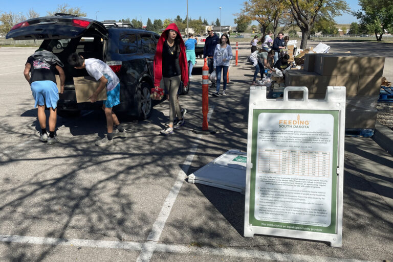 Students from Creekside Christian School in Rapid City help pack groceries into the trunks of cars during a recent mobile food bank event sponsored by Feeding South Dakota. South Dakota News Watch photo by Bart Pfankuch