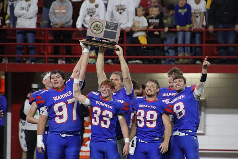 Warner head coach Kerwin Hoellein and players hold up the Class 9A football championship trophy. Aberdeen Insider photo by Robb Garofalo