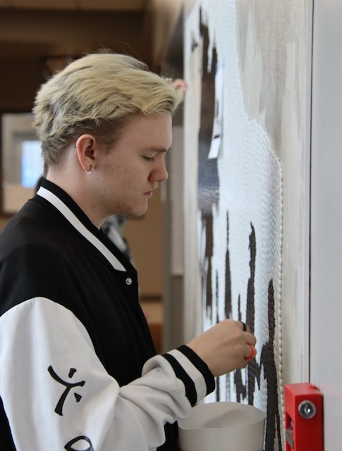 Lakota Flint adds white beads, about 11 millimeters in diameter, to a mural in the hallway at South Dakota School for the Blind and Visually Impaired. Aberdeen Insider photo by Elisa Sand