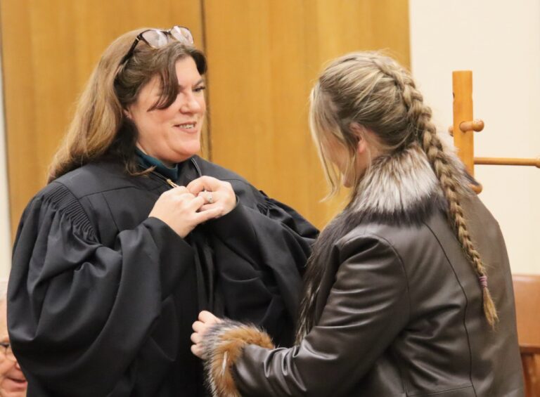 Julie Dvorak fastens the clasps with the aid of her daughter Annie on Friday, Jan. 26.