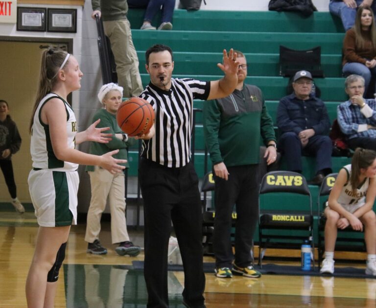 Andrew Wanner hands the ball to Aberdeen Roncalli's Rylee Moeller during a game at the Roncalli Gym. Wanner is officiating at this weekend's State B boys basketball tournament at the Barnett Center. Aberdeen Insider photo by Robb Garofalo
