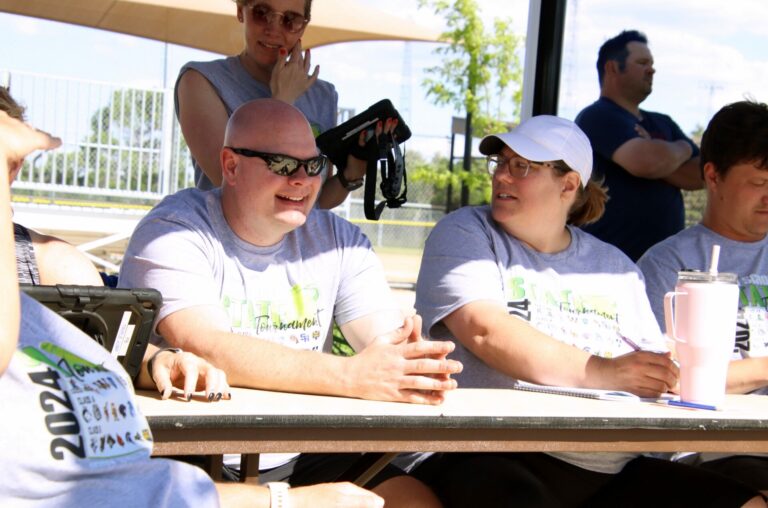 Central High School resource officer John Kirnan looks on during the West Central/Tea Area Class A softball state title game Saturday, June 1. At right is Tricia Gough. Behind Kirnan is Mickey Everson. Aberdeen Insider photo by Robb Garofalo.