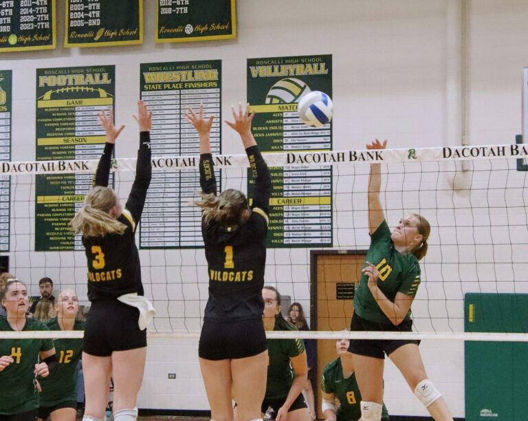 Aberdeen Roncalli's Morgan Helms attempts to hit through the block of Northwestern's Payton Grandpre (1) and Breelyn Satter Tuesday, Aug. 27 in high school volleyball action at the Roncalli Gym. Northwestern won the match. Aberdeen Insider photo by Robb Garofalo.