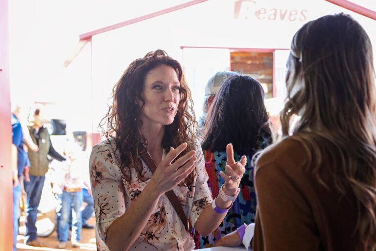 Rebecca Blue (left) shares information about a program to connect, engage and educate women in agriculture and conservation with Dakotafest Woman Farmer/Rancher of the Year nominee Kendra Olson on Aug. 22, 2024, at Dakotafest in Mitchell, S.D. (Photo: Kristi Hine/ South Dakota News Watch)