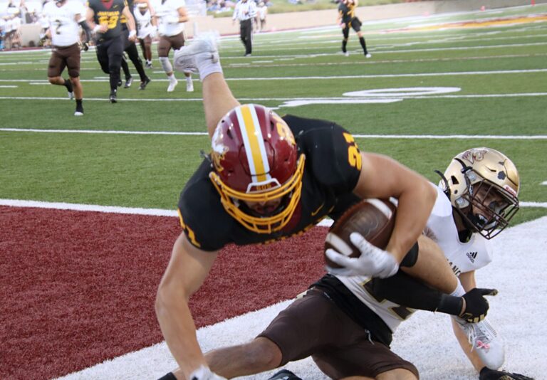 Northern State's Hank Kraft leaps into the end zone over Southwest Minnesota's Josiah Hedensen during the first quarter of their game Saturday, Oct. 19 in Dacotah Bank Stadium. The Wolves won 41-7. Aberdeen Insider photo by Robb Garofalo.