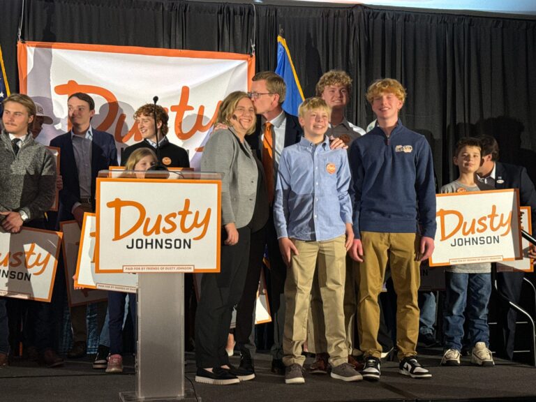 South Dakota Rep. Dusty Johnson kisses his wife, Jacquelyn, and stands with his three sons after declaring victory in his U.S. House re-election race at the Holiday Inn City Centre in Sioux Falls, S.D., on Nov. 5, 2024. South Dakota News Watch photo by Stu Whitney.