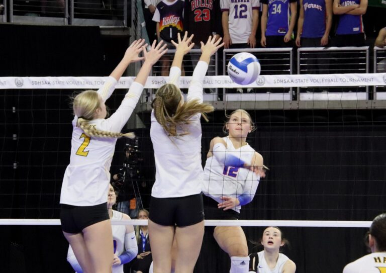 Warner's McKenna Leidholt hits around the block by Colman-Egan's Elaina Rhode, left, and Anna Zwart in the second set of their Class B volleyball match Thursday, Nov. 21 in the Denny Sanford PREMIER Center in Sioux Falls. The Monarchs advanced with a five-set victory. Aberdeen Insider photo by Robb Garofalo.