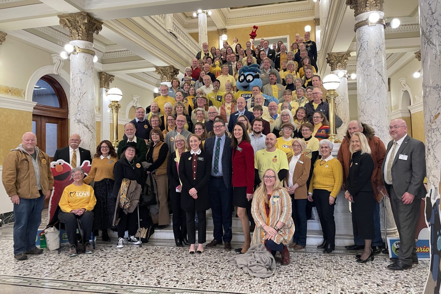 Busloads of public broadcasting supporters make case to avoid $3.6 million state budget cut 2 Supporters of South Dakota Public Broadcasting pose for a picture Feb. 7, 2025, on the Capitol Rotunda steps in Pierre. At center in the front row is Lt. Gov. Tony Venhuizen, alongside state Rep. Kadyn Wittman, D-Sioux Falls, left, and state Sen. Helene Duhamel, R-Rapid City. South Dakota Searchlight photo by Seth Tupper.