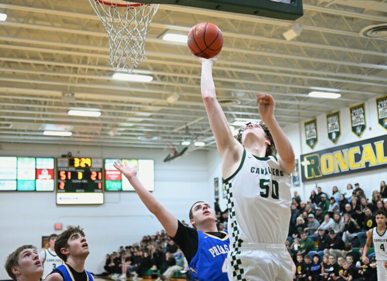 Aberdeen Roncalli's Cam Olson scores in front of Redfield's Ethan Falk during the third quarter of their Region 1A quarterfinal Tuesday, March 4 at the Roncalli Gym. Olson had 16 points to lead Roncalli to a 79-34 win. Aberdeen Insider photo by Robb Garofalo.