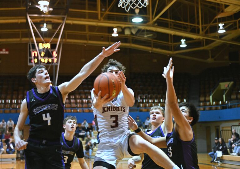 Aberdeen Christian's Luke Kaiser drives in between Waubay/Summit's Tigh Gaikowski, left, Dylan Rumpza and Camden Neilan during the Region 1B semifinal Saturday, March 8 at the Aberdeen Civic Arena. Kaiser had 13 points to help the Knights advance to the Class B SoDak 16. Aberdeen Insider photo by Robb Garofalo.
