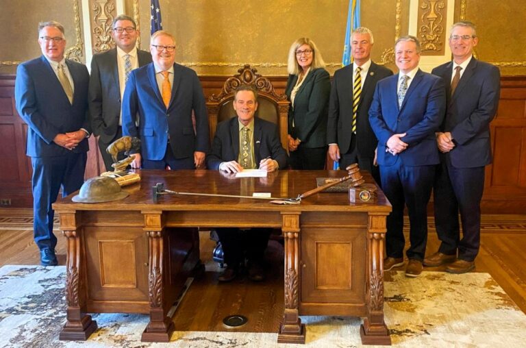 South Dakota Gov. Larry Rhoden signs Senate Bill 74, an open meetings bill, on Feb. 12, 2025, in his office at the Capitol. From left: South Dakota NewsMedia Association’s David Bordewyk, Lt. Gov. Tony Venhuizen, Sen. Tim Reed, Gov. Rhoden, Rep. Mary Fitzgerald, Attorney General Marty Jackley, SDNA lobbyist Justin Smith and Sen. Steve Kolbeck. Photo courtesy of South Dakota News Media Association.