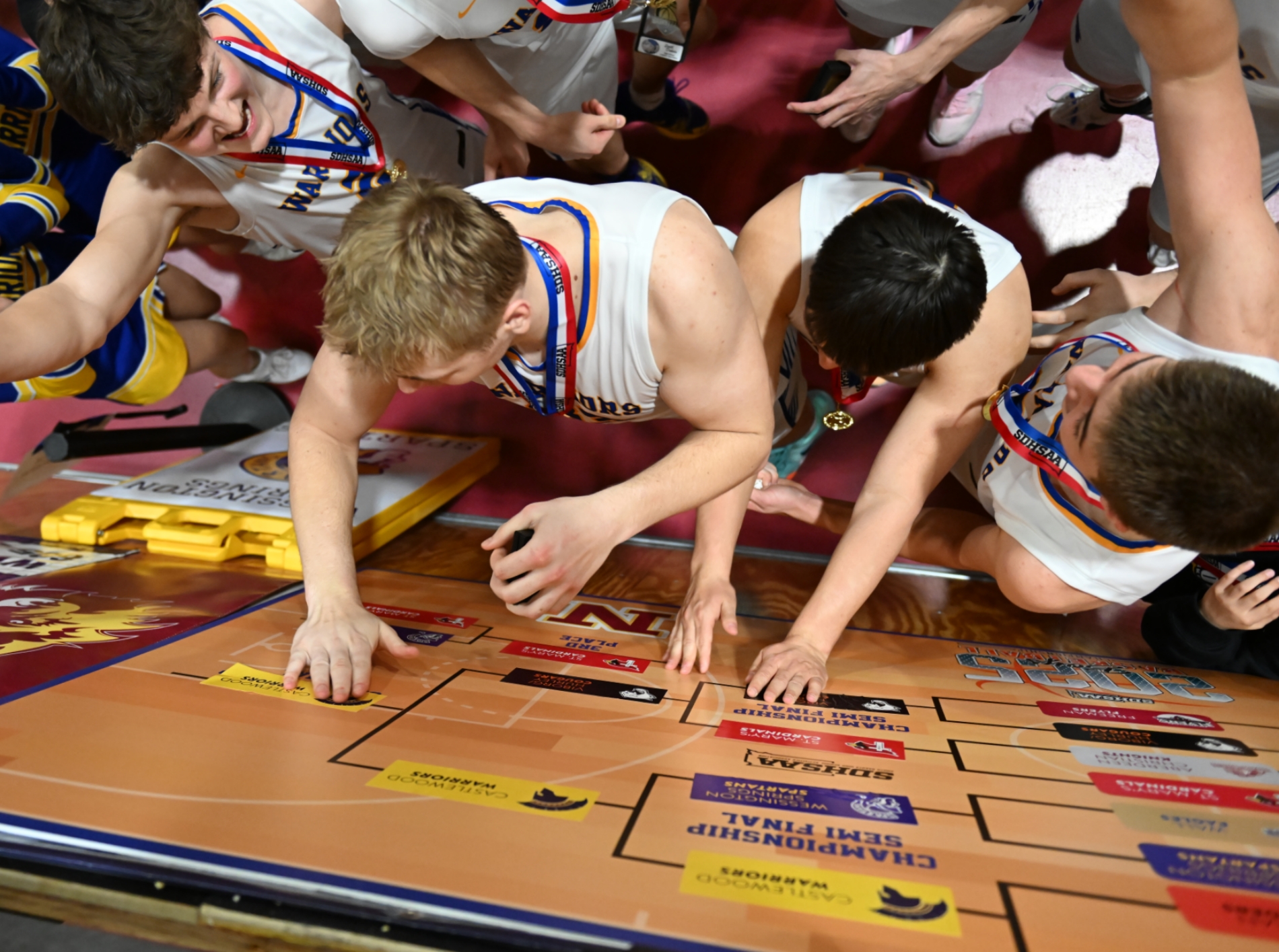 A view from above as Bryon Laue, center, and his Castlewood teammates place their team sticker on the champions line of the 20205 State B tournament bracket following their 52-31 win over Viborg-Hurley. Aberdeen Insider file photo.