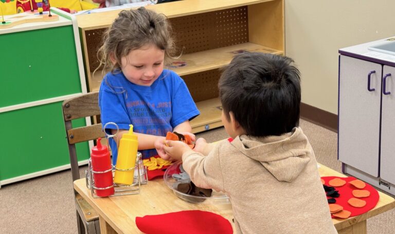 Harper Nelson accepts a handful of play food items from Tyler Falcon in a kitchen space created in a Head Start classroom in Aberdeen. Aberdeen Insider photo by Elisa Sand.