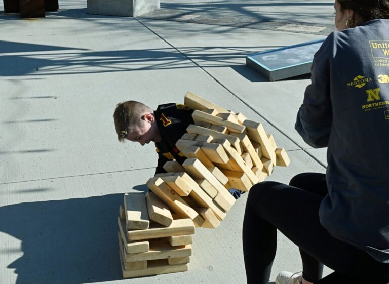 Aberdeen's Owen Finer tumbles the blocks during a game of Jenga Saturday, May 3 at Northern's State Day of Champions at the Plaza on Main. Looking on is Northern softball player Kennadi Deckert. Aberdeen Insider photo by Robb Garofalo