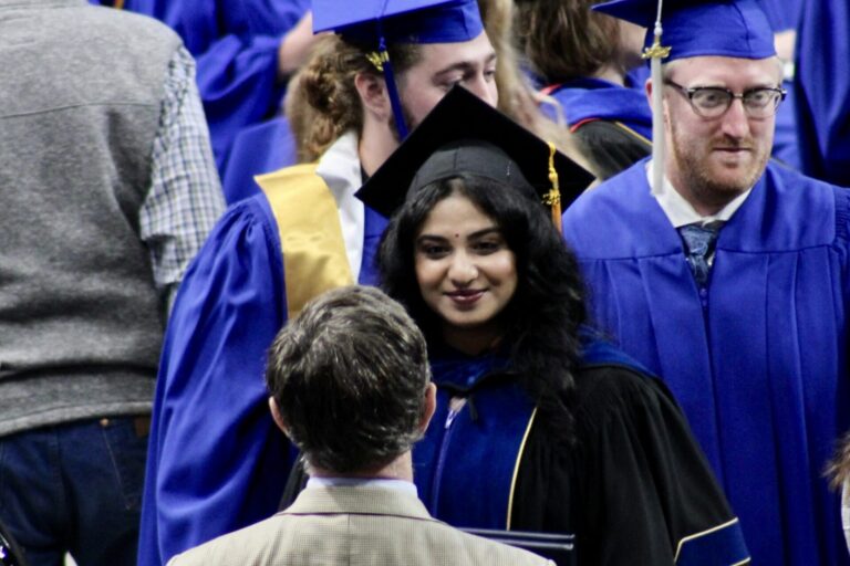 Priya Saxena, center, receives congratulations from her attorney, Jim Leach, foreground, after graduating with a master’s and doctoral degree from South Dakota Mines on May 10, 2025, in Rapid City. South Dakota Searchlight photo by Seth Tupper.