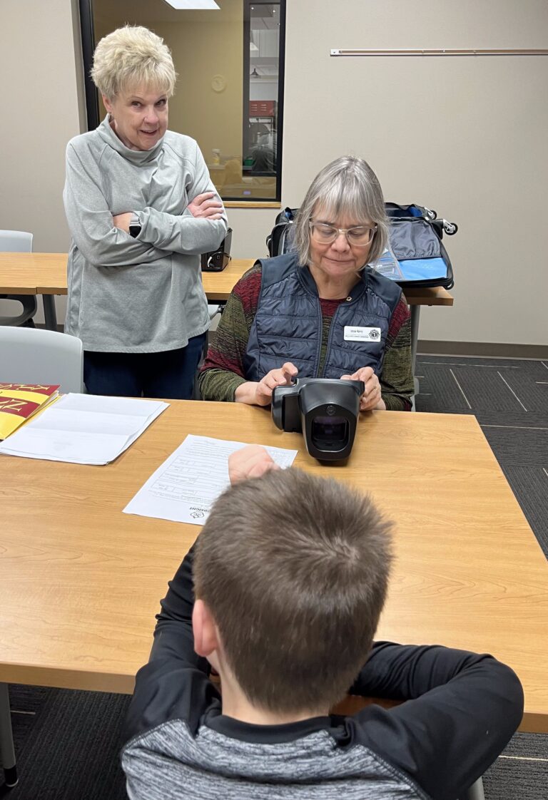Paige Anderson, standing, and Judy Albl with the Aberdeen Lioness Lions Club screen the vision of a youngster. Courtesy photo.