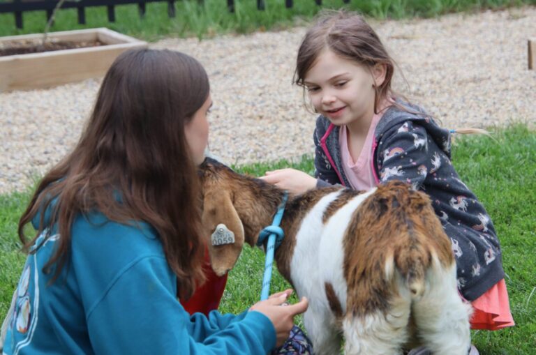 Eleanor Kollman, right, was one of several children who stopped to pet the goat brought by Payton Miller for the petting zoo at the K.O. Lee Aberdeen Public Library. Aberdeen Insider photo by Elisa Sand.