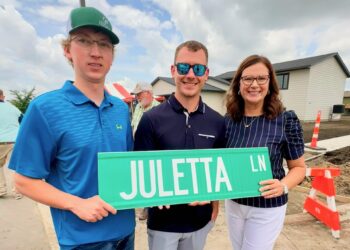 Family members of Juletta Smith, from left, Evan and Brent Dutenhoffer and Catherine Smith, hold the street sign recognizing her work with Homes Are Possible, Inc. Photo courtesy of Homes Are Possible.