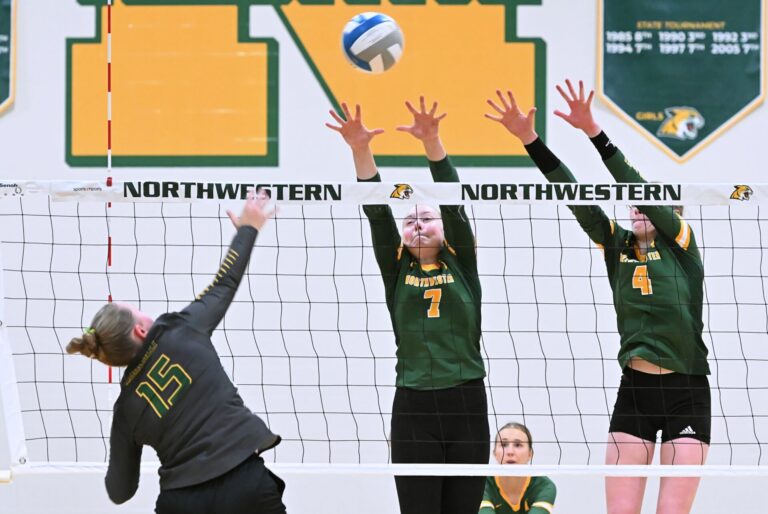 Aberdeen Roncalli's Reese Heinrich tries to hit over the block attempt of Northwestern's Lila Johnson (7) and Ashley Haven during the third set Tuesday, Aug. 26 in Mellette. Aberdeen Insider photo by Allie Hoekman.