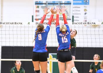 Aberdeen Roncalli's Grace Cogley gets blocked at the net by Warner's Lily Meehan (15) and Miah Leidholt of Warner during the second set of their match Tuesday, Sept. 30 inside the Roncalli Gym. Warner won in straight sets. Aberdeen Insider photo by Robb Garofalo.