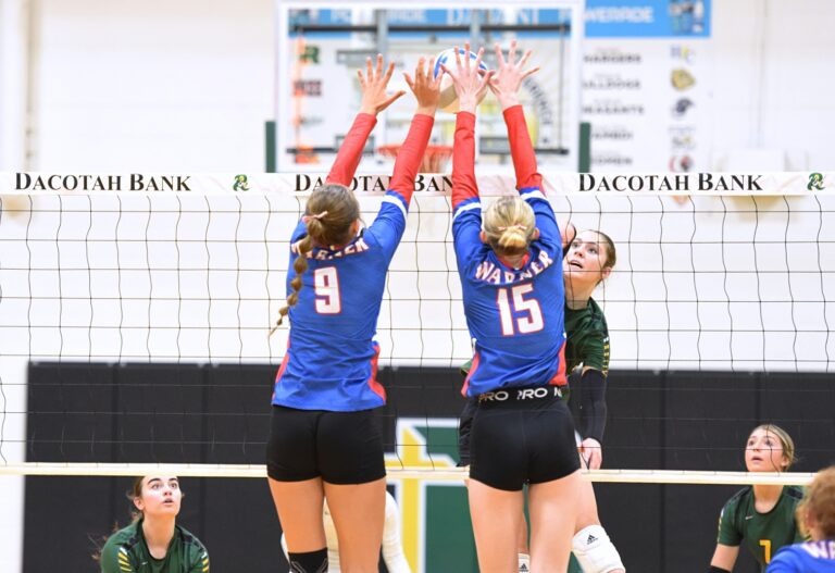 Aberdeen Roncalli's Grace Cogley gets blocked at the net by Warner's Lily Meehan (15) and Miah Leidholt of Warner during the second set of their match Tuesday, Sept. 30 inside the Roncalli Gym. Warner won in straight sets. Aberdeen Insider photo by Robb Garofalo.