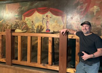 Jason Knowles, assistant professor of art and digital media at Northern State University, in front of a mural at the Roadhouse in Hawthorne, Wis. A similar mural is the centerpiece of what will be a locally produced paranormal film. Courtesy photo.