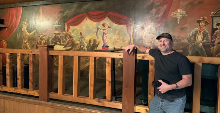 Jason Knowles, assistant professor of art and digital media at Northern State University, in front of a mural at the Roadhouse in Hawthorne, Wis. A similar mural is the centerpiece of what will be a locally produced paranormal film. Courtesy photo.