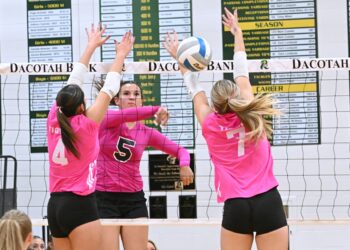 Aberdeen Roncalli's Gabby Thomas hits through the block attempt of Mobridge-Pollock's Pacey Konold and Blake Thompson during the second set of a three-set sweep by Roncalli Tuesday, Oct. 14 inside Roncalli Gym. Aberdeen Insider photo by Robb Garofalo.