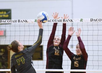 Aberdeen Roncalli's Grace Cogley tips the ball over the block attempt by Milbank's Avery Schuneman (12) and Zora Henrich during their Region 1A match Tuesday, Nov. 4 at the Roncalli Gym. Roncalli advanced in straight sets. Aberdeen Insider photo by Robb Garofalo.