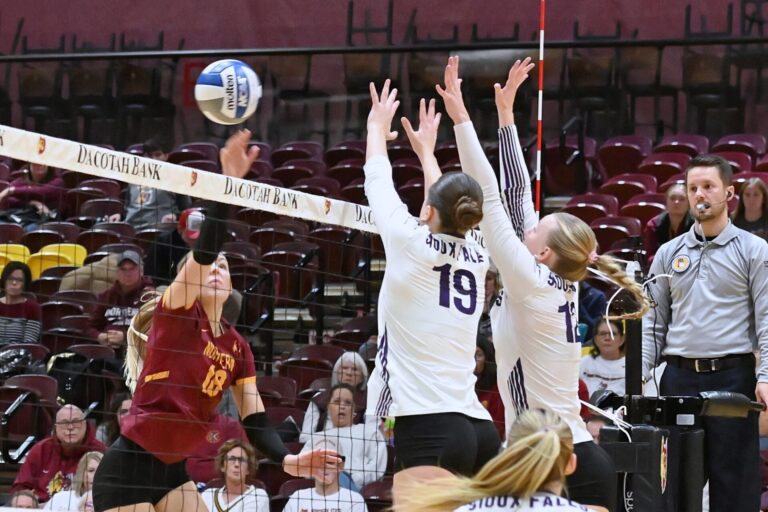 Northern State's Linnea Neisham tips the ball over the block attempt by Sioux Falls' Ella Walker (19) and Abby Haus during the third set of their match Saturday, Nov. 7 inside Wachs Arena. The Wolves were swept by the Cougars 25-19, 28-26, 25-21. Aberdeen Insider photo by Robb Garofalo.