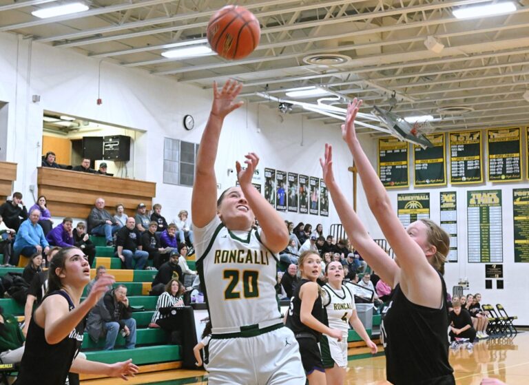 Aberdeen Roncalli's Rylee Voeller attempts a layup in between Waubay/Summit's Addison Heinje, left, and Mackenzie Zubke during the third quarter of Cavalier Classic Saturday, Dec. 20 at the Roncalli Gym. Voeller had nine points, helping Roncalli to a 48-43 win. Aberdeen Insider photo by Robb Garofalo.