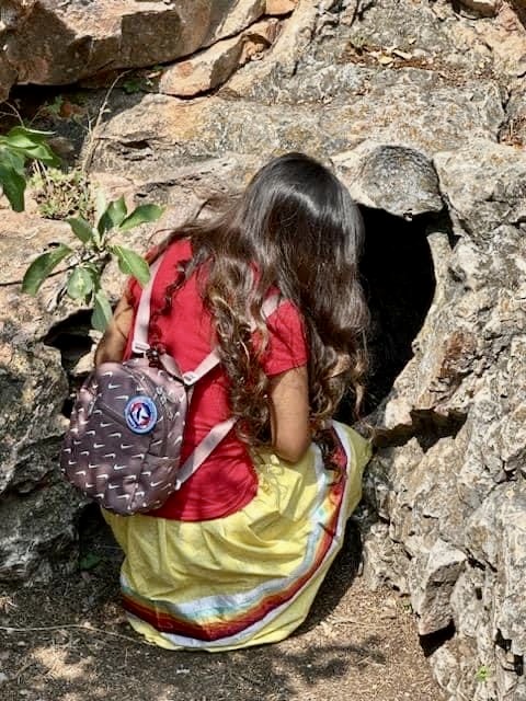 A girl kneels in front of a rock formation at Wind Cave National Park, which is a sacred site to the Lakota people. Photo courtesy of the South Dakota Native Tourism Alliance.