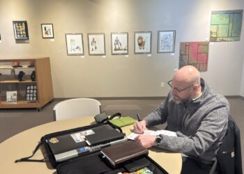Aberdeen artist Aaron Bigelow draws in his sketchbook at the Aberdeen Recreation & Cultural Center. In the background are some of his drawings of characters from "The Wonderful Wizard of Oz." Aberdeen Insider photo by Shannon Marvel.