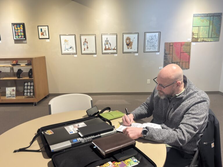 Aberdeen artist Aaron Bigelow draws in his sketchbook at the Aberdeen Recreation & Cultural Center. In the background are some of his drawings of characters from "The Wonderful Wizard of Oz." Aberdeen Insider photo by Shannon Marvel.