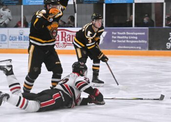 Aberdeen forward Jibber Kuhl reaches for the puck while he slides on the ice during the first period against Austin Saturday, March 7 at the Odde Ice Center. Defending for Austin are Kade Overrocker, left, and Kyle Sorenson. The Bruins won the game 3-2 to split the weekend series. Aberdeen Insider photo by Robb Garofalo.