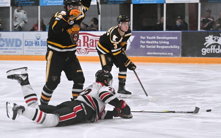 Aberdeen forward Jibber Kuhl reaches for the puck while he slides on the ice during the first period against Austin Saturday, March 7 at the Odde Ice Center. Defending for Austin are Kade Overrocker, left, and Kyle Sorenson. The Bruins won the game 3-2 to split the weekend series. Aberdeen Insider photo by Robb Garofalo.