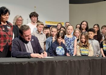 South Dakota Gov. Larry Rhoden signed House Bills 1017 and 1262 during a visit to Holgate Middle School on Friday, March 27. With the bills, an alternative learning center for disruptive students will be established in Aberdeen. Looking over Rhoden's shoulder is Rep. Lana Greenfield, R-Doland, the prime sponsor of HB 1262, which provides $2 million to make the facility a reality. Aberdeen Insider photo by Scott Waltman.