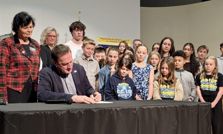 South Dakota Gov. Larry Rhoden signed House Bills 1017 and 1262 during a visit to Holgate Middle School on Friday, March 27. With the bills, an alternative learning center for disruptive students will be established in Aberdeen. Looking over Rhoden's shoulder is Rep. Lana Greenfield, R-Doland, the prime sponsor of HB 1262, which provides $2 million to make the facility a reality. Aberdeen Insider photo by Scott Waltman.