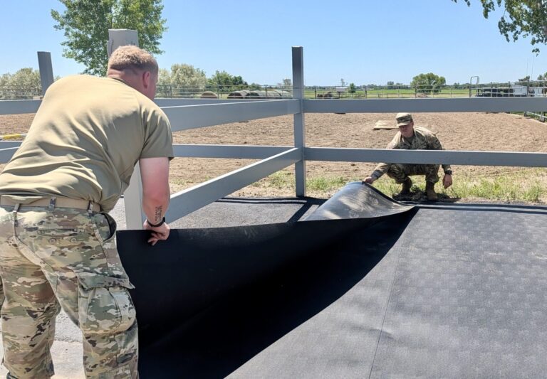 Braxton Farmen, in foreground, and Jaimen Farrell of Aberdeen, help put a mat down in a cross-tie area at SPURS Therapeutic Horseback Riding Center just north of Aberdeen on Saturday, June 6. Members of the South Dakota National Guard 740th Transportation Co. helped make a series of improvement at SPURS. Aberdeen Insider photo by Scott Waltman.