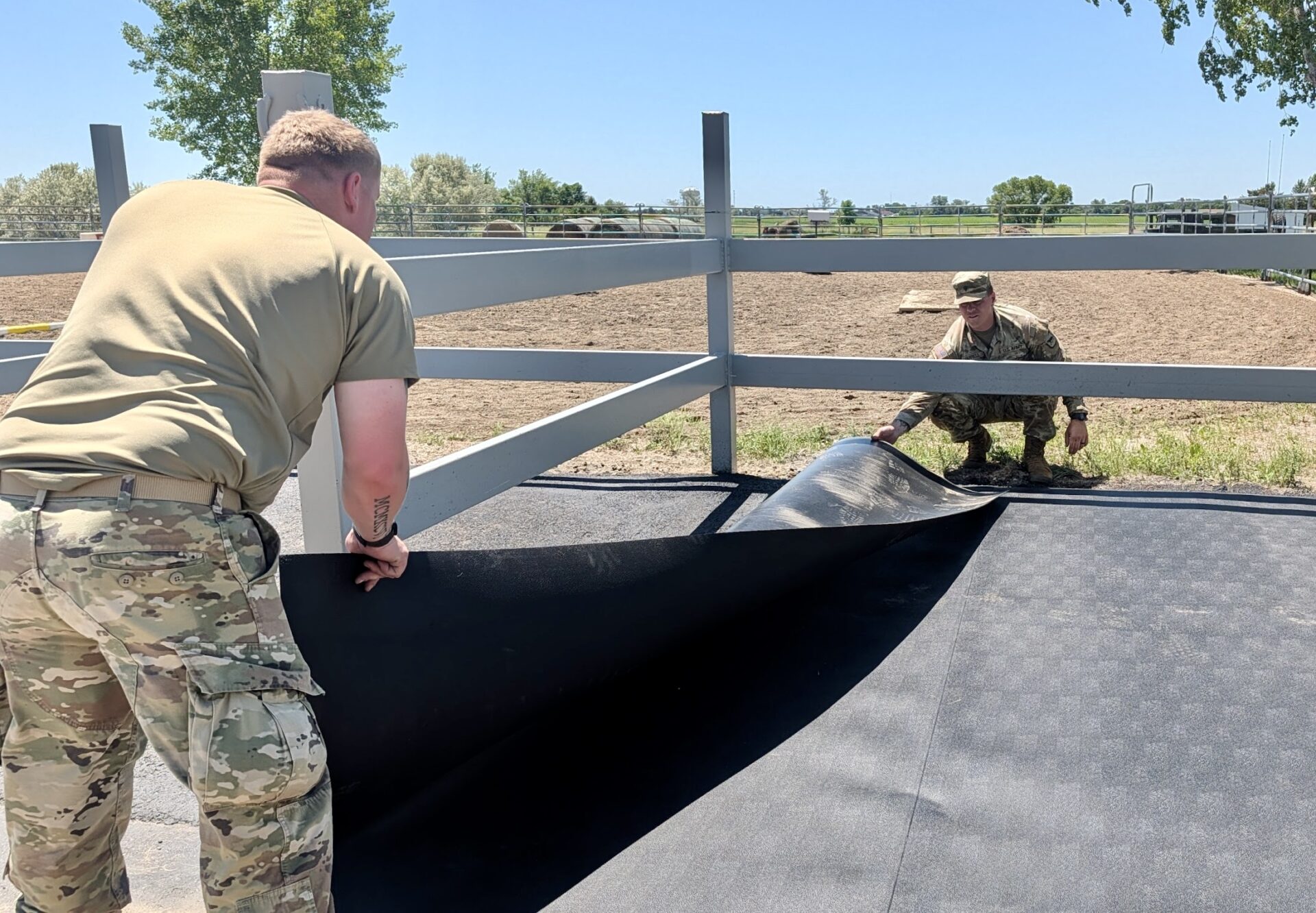 Braxton Farmen, in foreground, and Jaimen Farrell of Aberdeen, help put a mat down in a cross-tie area at SPURS Therapeutic Horseback Riding Center just north of Aberdeen on Saturday, June 6. Members of the South Dakota National Guard 740th Transportation Co. helped make a series of improvement at SPURS. Aberdeen Insider photo by Scott Waltman.