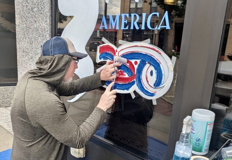Brian Schuck of Artful Aberdeen paints an exterior window on a building near the Capitol Theatre in downtown Aberdeen. It was one of about 15 window paintings in advance of Independence Day, when the U.S. will celebrate its 250th anniversary. One of the main local activities is a parade through downtown that begins at 10 a.m. on Saturday, July 4. Schuck was doing the painting for the Aberdeen Downtown Association. Aberdeen Insider photo by Scott Waltman.