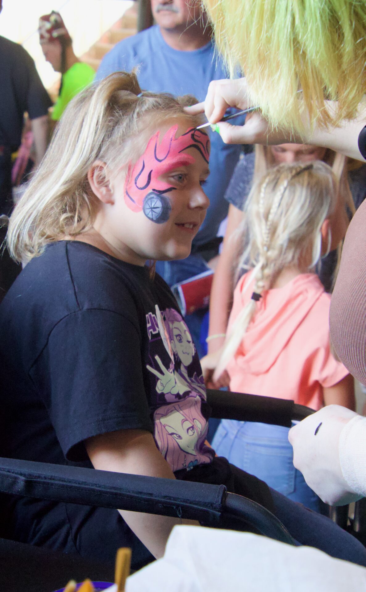 Molly Stevens sits patiently under the grandstand at the Brown County Speedway Friday, July 31 as she gets her face painted by Jada Volk. Aberdeen Insider photo by Elisa Sand.