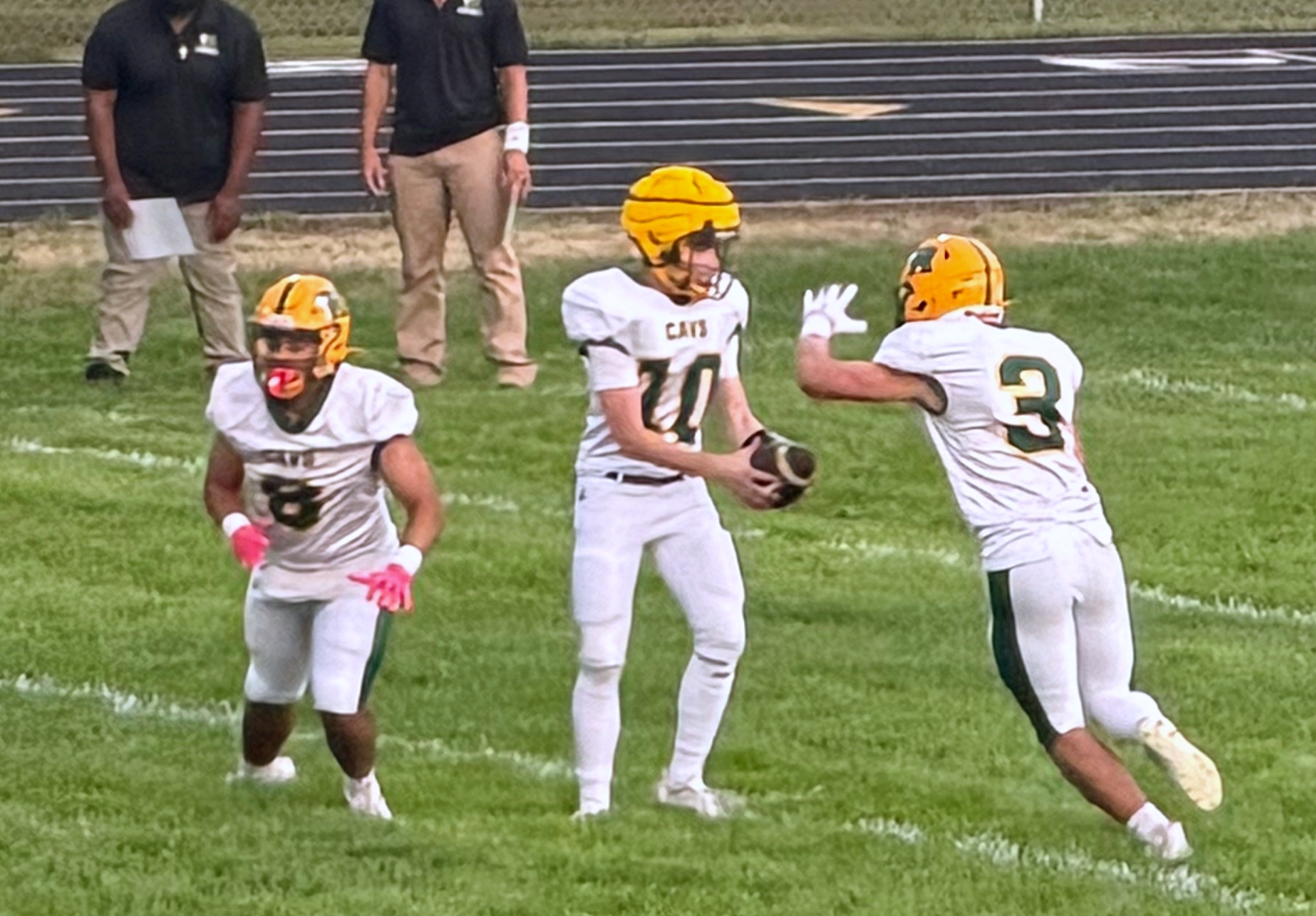 Aberdeen Roncalli's Austin Fisher hands the ball off to Will Haskell during the first quarter against Sioux Valley Friday, Aug. 21 in Volga. Roncalli's Jean Anthony Thomas leads the way as a blocker. Photo courtesy Dan Richardt.