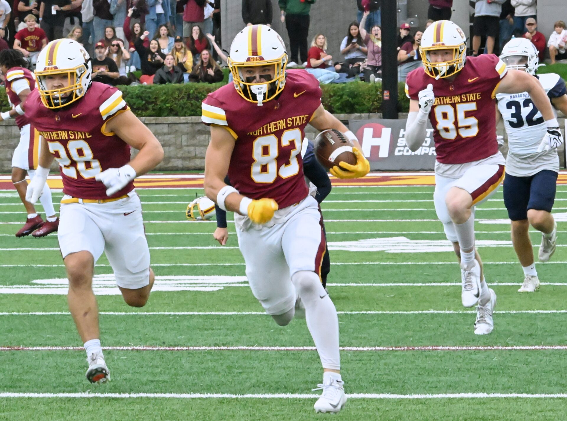 Cooper Eisenbeisz, flanked by Layne Johnson (28) and Brock Ellingson (85), takes the opening kickoff 87 yards for a touchdown against the University of Mary during Gyps Day Saturday, Sept. 26 at Dacotah Bank Stadium. Northern won the game 21-14. Aberdeen Insider photo by Robb Garofalo.